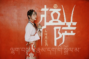 一位年轻女孩站在一幅红墙前 上面有中国书法。