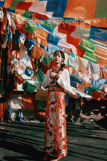 一位穿着传统服装的女性站在国旗下