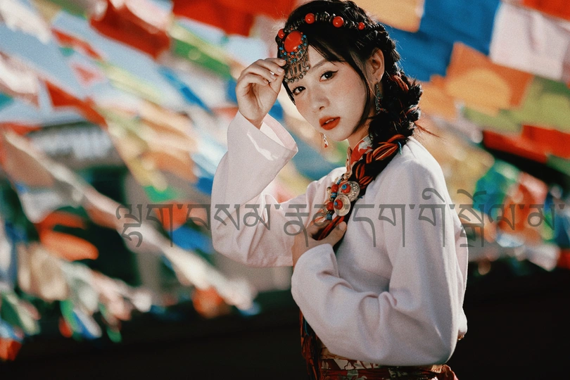 一位身着传统服装的年轻女子在彩色旗帜前摆姿势