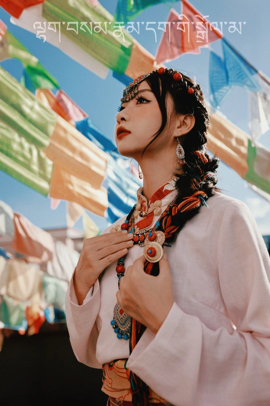 一位穿着传统裙子的年轻女子站在彩色旗帜前