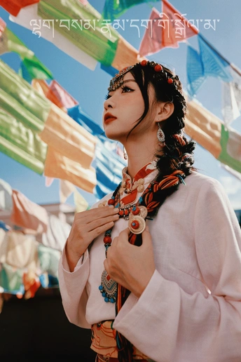 一位穿着传统裙子的年轻女子站在彩色旗帜前