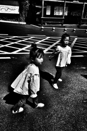 两个小女孩站在停车场里 一个年轻的孩子穿过街道。
