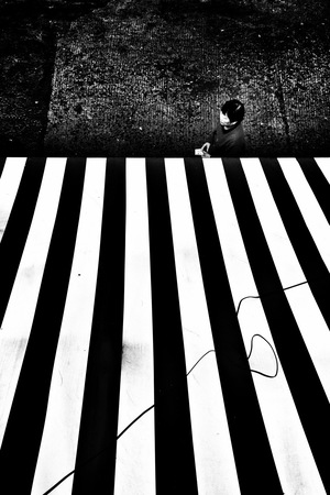 一个人坐在街道地板上 地板上有黑色和白色线条。