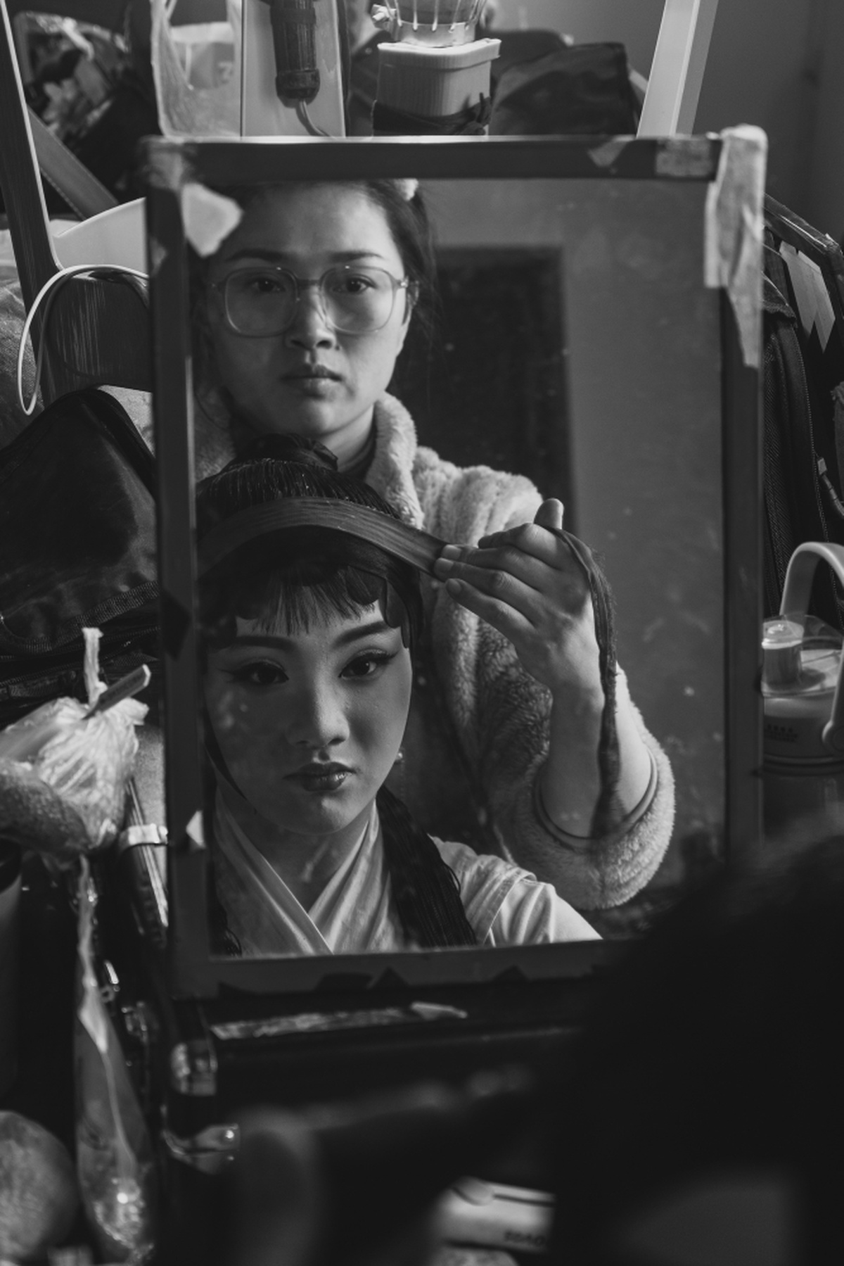 一张黑白照片 一位女士正在镜子前看她的头发。