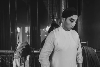 一个年轻人站在一个挂满衣服的衣架上 穿着一件衬衫。