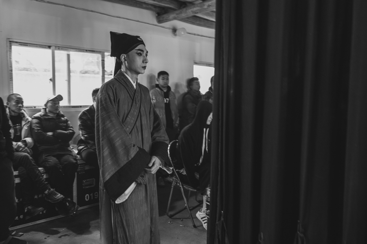 一张黑白照片 毕业生走进一个有其他学生站立的房间。