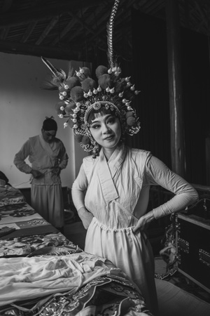 黑白照片 一位穿着有花饰的头饰的女人站在床前