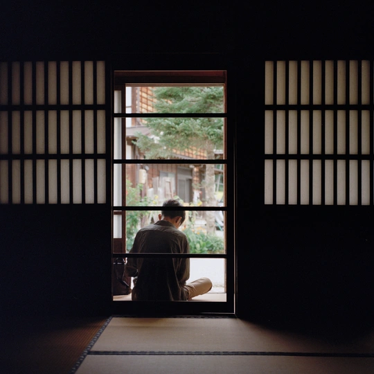 一个人坐在房间里 透过打开的窗户向外看