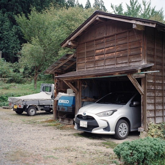 一辆小汽车和卡车停在木质房屋或谷仓的车库里