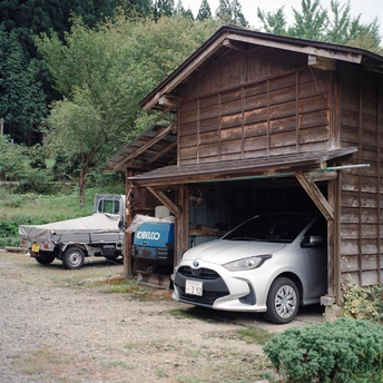 一辆小汽车和卡车停在木质房屋或谷仓的车库里