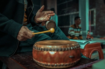 一个男子在木桌上弹奏乐器 其他人在背景中坐着。