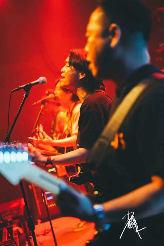 图片可能包含人、舞台上、演奏乐器、夜晚和室内。