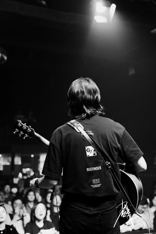 一张黑白照片 描绘了一个在音乐会舞台上演奏乐器的人在人群前。