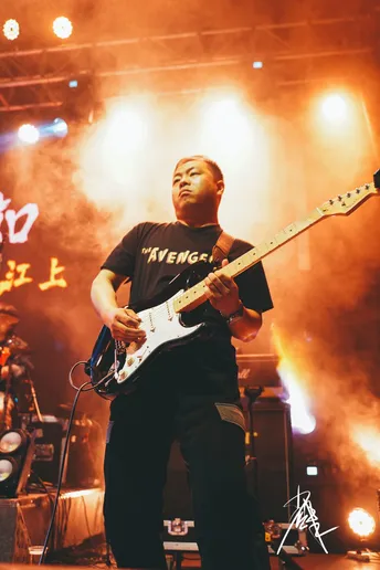 图片可能包含一个人在舞台上弹奏乐器 夜晚和音乐会。