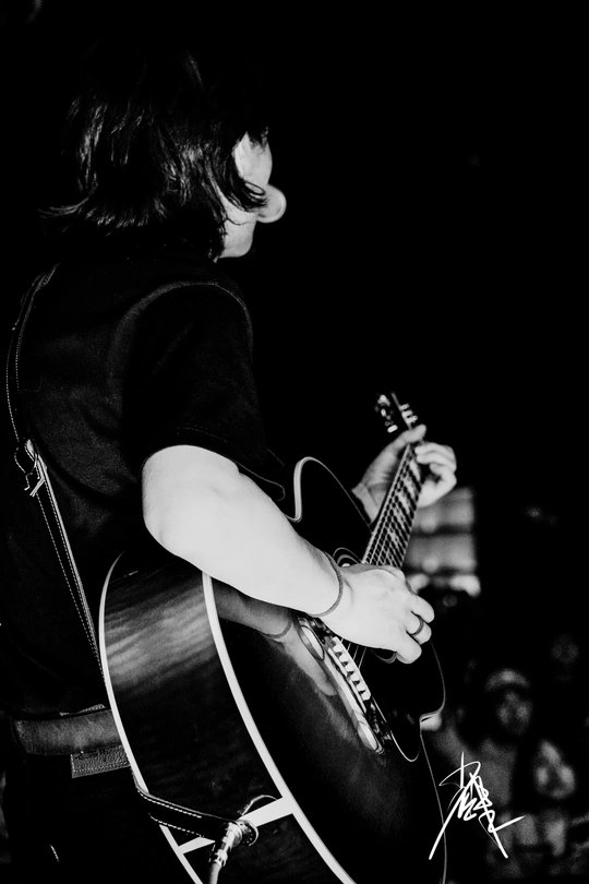 一个黑白图像 描绘的是一个人在夜晚舞台上演奏乐器。