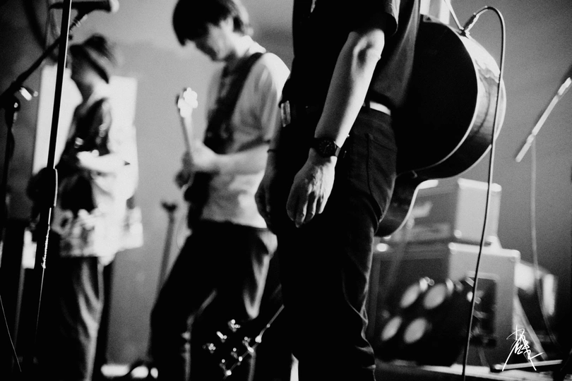 一张黑白照片 一个人在舞台上演奏乐器 背景有一群人组成的乐队。