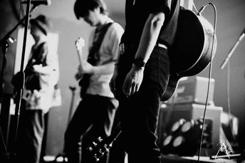 一张黑白照片 一个人在舞台上演奏乐器 背景有一群人组成的乐队。