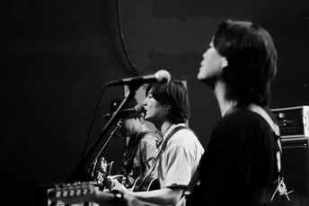 一个黑白图像 描绘一个人在晚上舞台上与乐队一起演奏乐器。