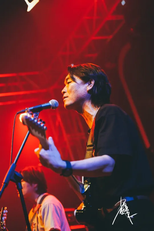 图片可能包含一个人在舞台上弹奏乐器 夜晚 音乐会和麦克风。