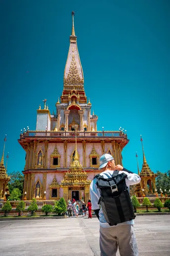 一个背着背包的男子站在寺庙前 仰望着塔。