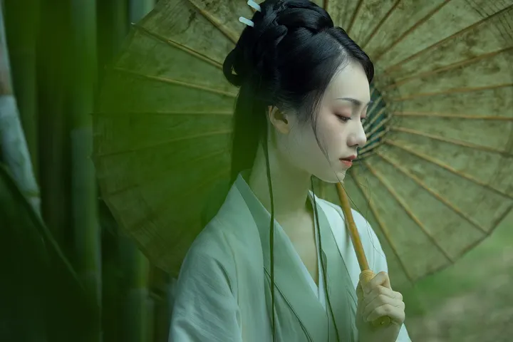 “纤手执素伞，胧雨漫竹林”