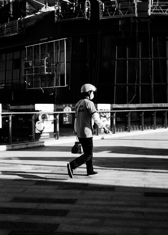 一张黑白照片 一个男子正在街上走。