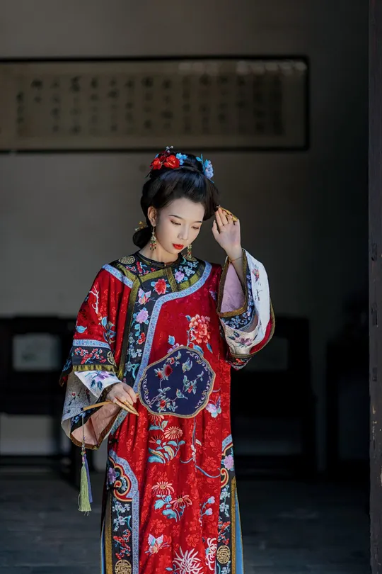 一位穿着传统服装的年轻女子 身着红白相间的和服 站在一栋建筑物的门口。