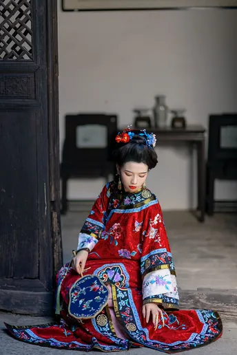 一个穿着传统服装的年轻女孩坐在建筑物地板上 身着红色和服。