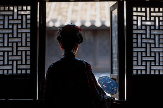 一个站在黑暗房间里的女人 正在透过窗户向外看。