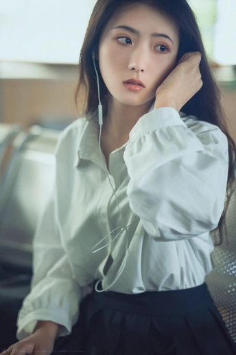 一个穿着白色上衣坐在沙发上的年轻女子