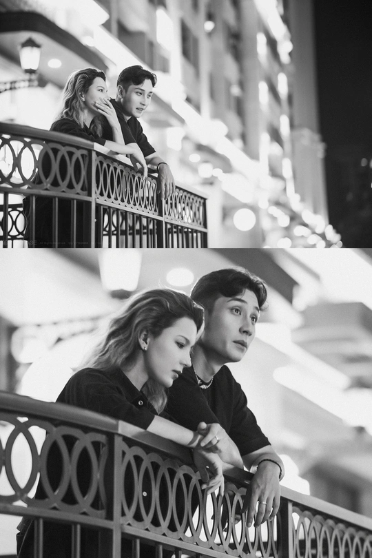 一张黑白照片 照片中一男一女晚上站在桥上越过围栏观看