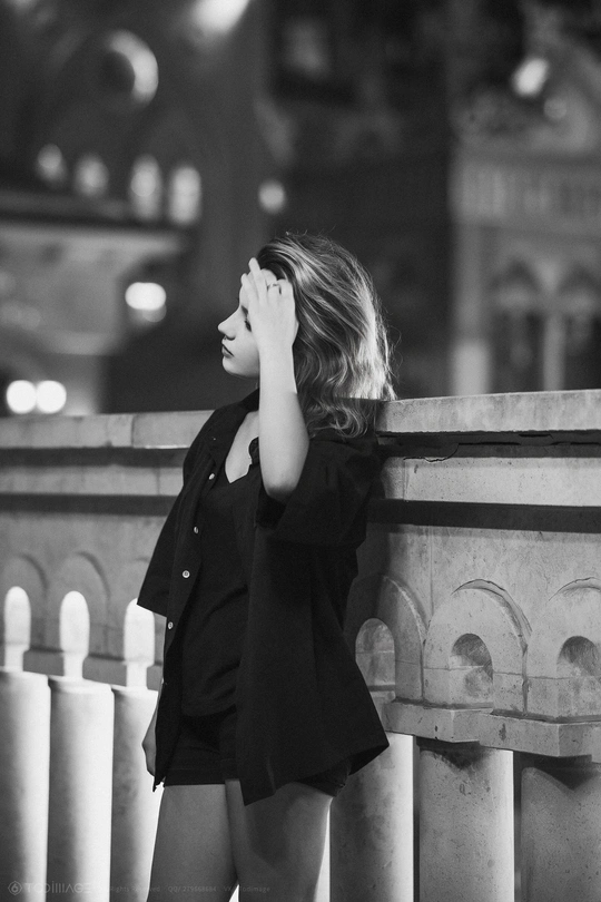 一张黑白照片 照片中一名年轻女子靠在一栋大楼上 手放在脸上