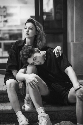 一张黑白照片 一对年轻的男孩和一对女人坐在一栋楼的台阶上