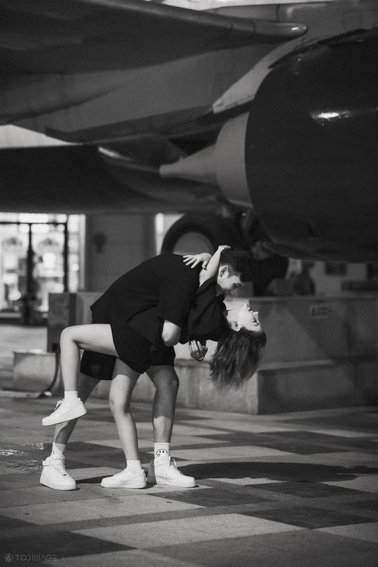 一张黑白照片 照片中一名年轻女子在飞机前做手势