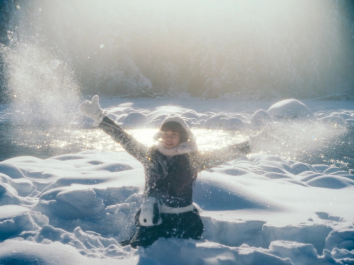 一位年轻女子站在雪中 双手举过头顶
