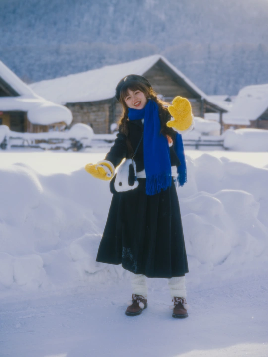 一个小女孩站在雪地里拿着雪板