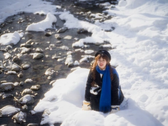 一个年轻女子坐在雪水旁边