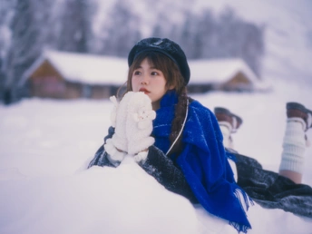 一个小女孩穿着蓝色衣服坐在雪地里抱着一个小毛绒玩具