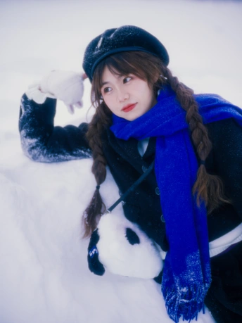一位戴帽子和蓝色围巾的年轻女子在雪中