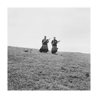 黑白照片 一对穿着传统服装的男女站在山顶。