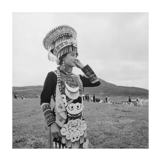 黑白照片 一位身着传统服装的年轻女孩站在田野中。