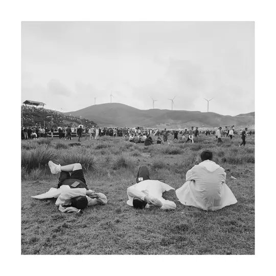 一张黑白照片 人们坐在毛毯上 背景是山坡。