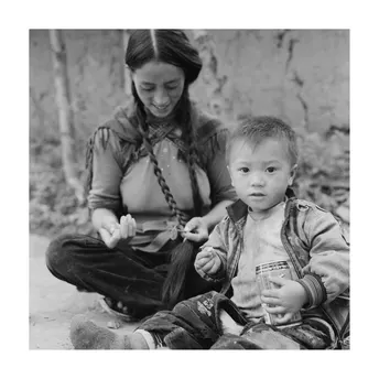 一张黑白照片 一位年轻女子坐在一个小孩子旁边。