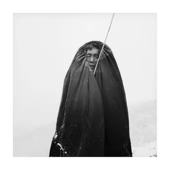 一张黑白照片 一个戴斗篷的男子站在雪中