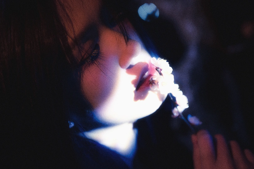 一个年轻女孩含着花在打电话