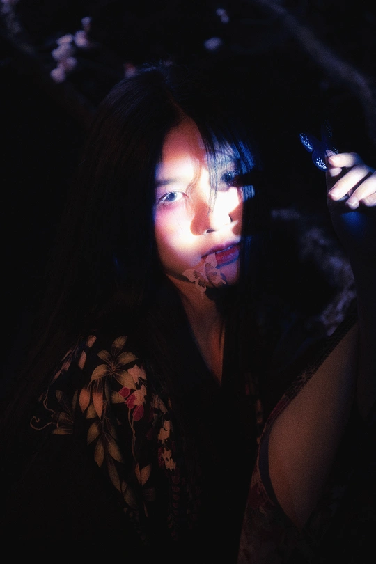 一个年轻女子在一个黑暗的房间里拿着手机对着脸