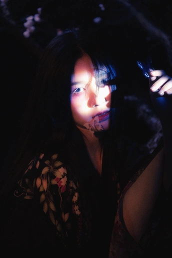 一个年轻女子在一个黑暗的房间里拿着手机对着脸