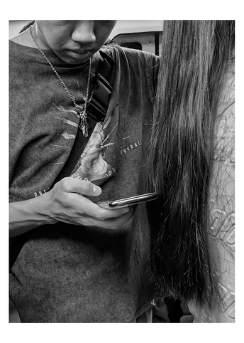 一位年轻女子手里拿着手机 低头看着她的头发