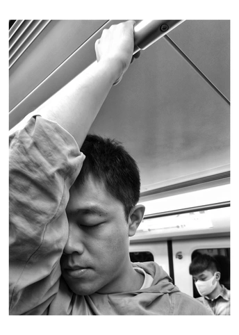 一个年轻男子在地铁或火车上睡觉 抱着他的头