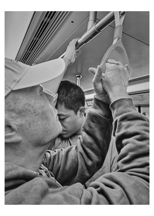 一张黑白照片 一位老人抱着一个戴帽子的小男孩